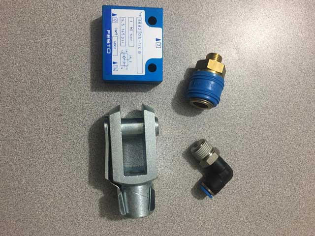 Kit de componentes neumáticos incluyendo clevis, racores y sensores de posición.